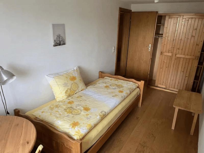 Einzelzimmer mit Holzbett und Kleiderschrank